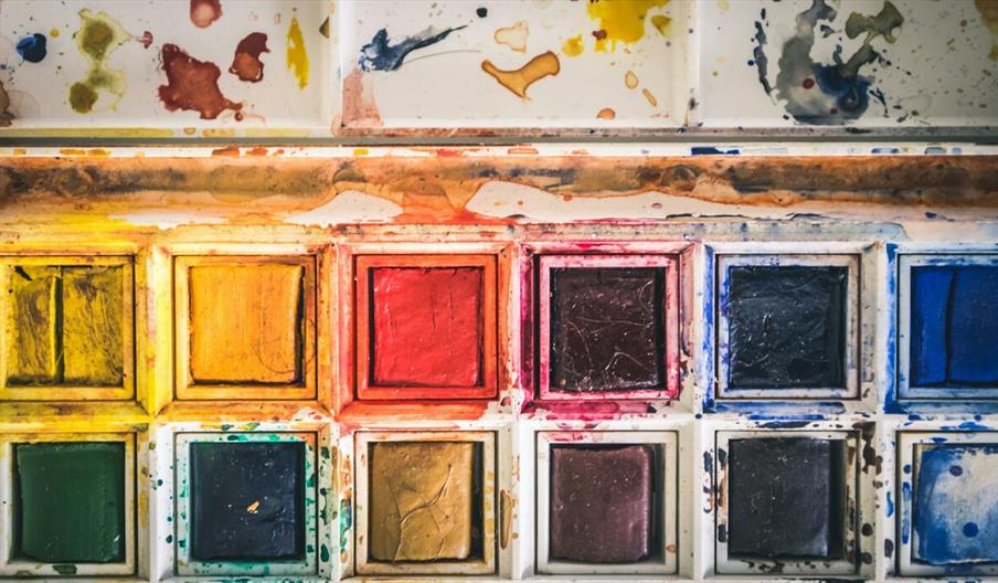 Colourful close-up of used watercolor paint palette with vibrant hues