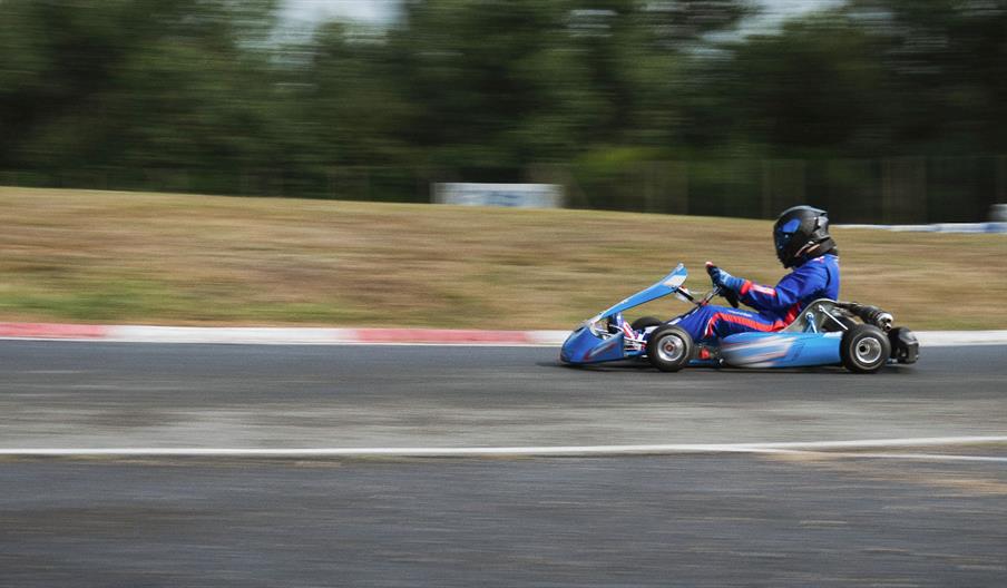 A blue go kart speeding across a track